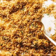 Golden breadcrumbs on a sheet pan with a spoon.