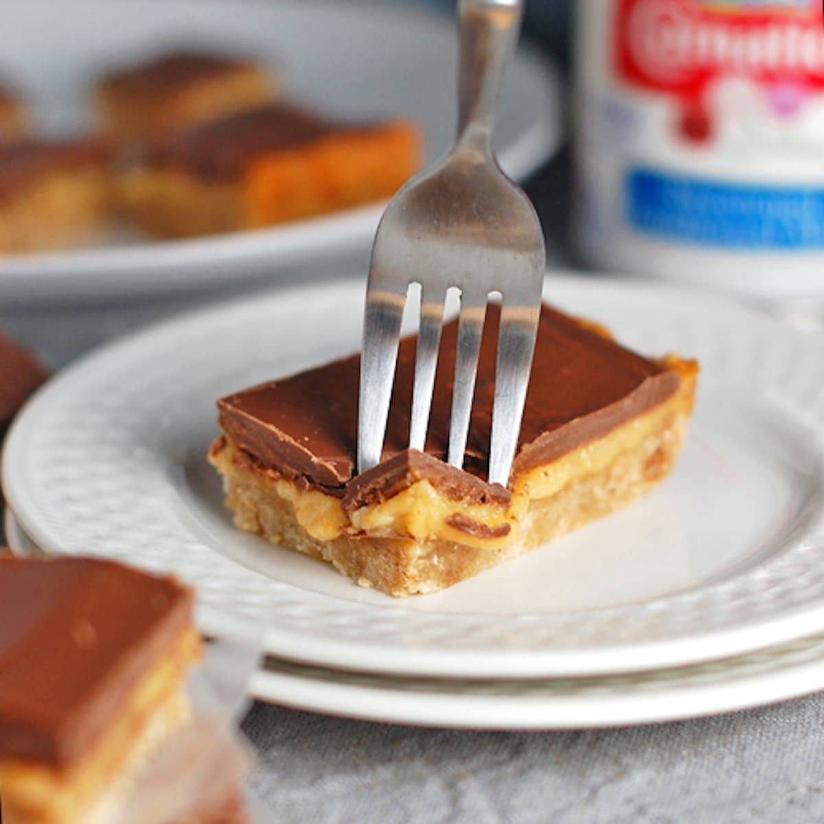 Fork in a milk chocolate dulce de leche bar on a white plate.
